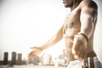 Midsection of shirtless man with arms raised against white background