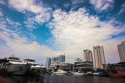 Boats in harbor against cloudy sky