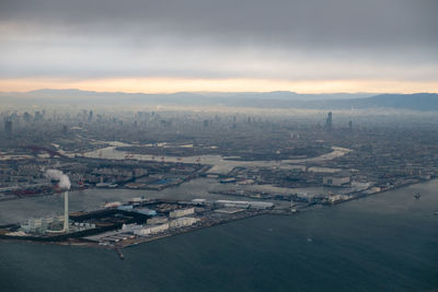 High angle view of city by sea against sky