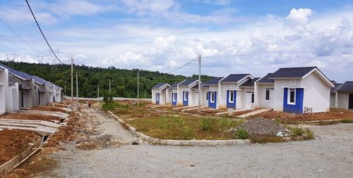 Houses by road amidst buildings against sky