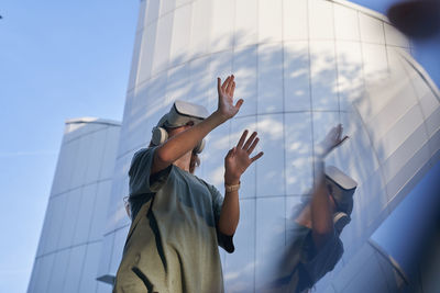 Teenage girl in vr helmet in the park on background of modern building 