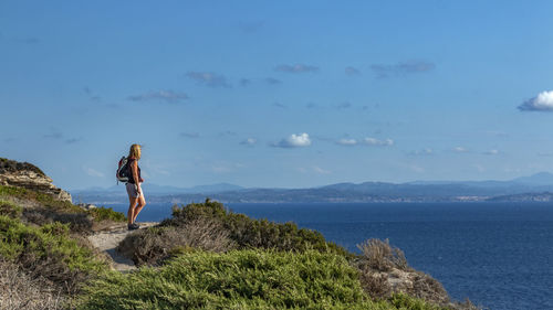 Side view of backpacker looking at sea against sky