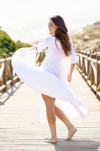 Woman holding dress while standing on footbridge