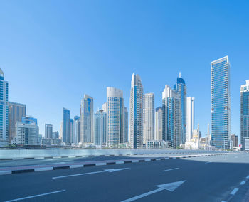 View of city buildings against clear blue sky