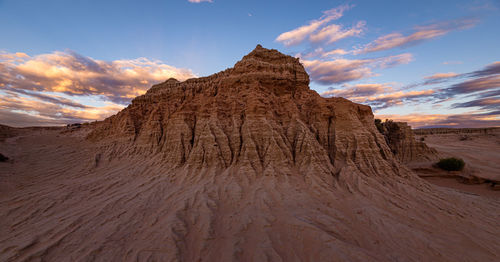 Rock formations on landscape against sky during sunset