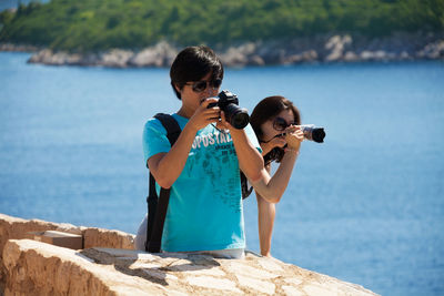 Siblings and woman standing at sea shore