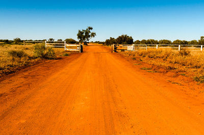 Dirt road along landscape against clear sky