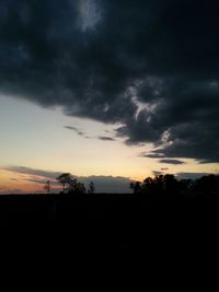 Silhouette of trees against cloudy sky