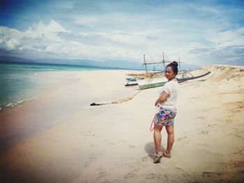 Full length of young woman on beach against sky