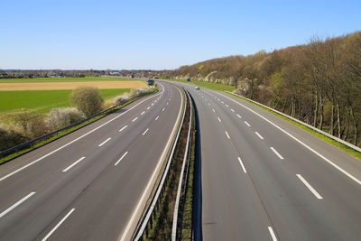 Aerial view of road amidst trees against clear sky