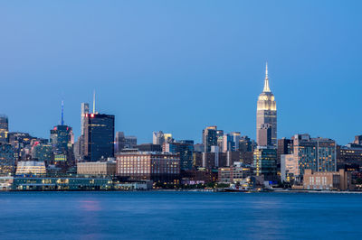 City at waterfront against blue sky