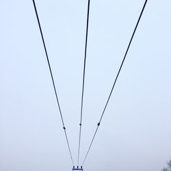 Low angle view of power lines against clear sky