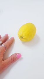 Close-up of woman hand by lemon over white background