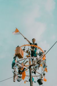 Low angle view of people on rope against sky