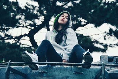 Young woman sitting against trees