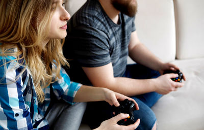 Young couple playing video game while relaxing on sofa at home