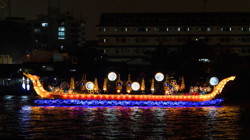 Illuminated buildings by river in city at night