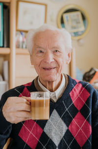 Portrait of smiling senior man holding drink