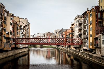 Footbridge over river amidst buildings