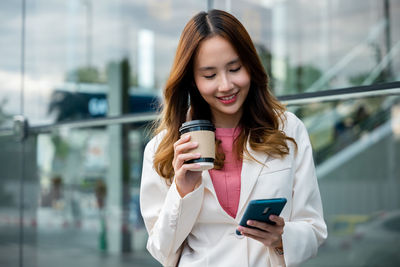 Portrait of young woman using mobile phone in city