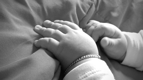 Cropped hands of baby on bed