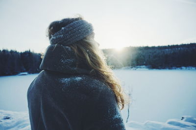 Rear view of woman on snow field against clear sky