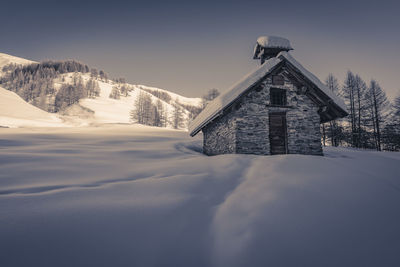 Built structure on snow covered mountain against sky