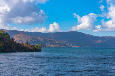 Scenic view of sea by mountains against sky