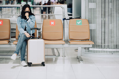 Woman wearing mask sitting on chair at airport