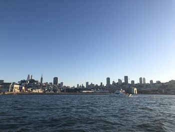Sea by buildings against clear blue sky