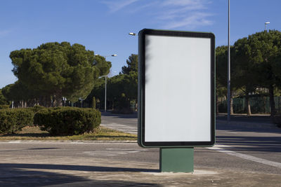 Road sign by street in city against sky