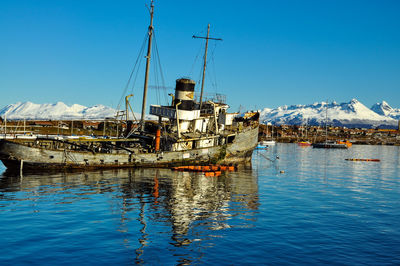 Old boat moored in harbor at beagle channel against clear blue sky