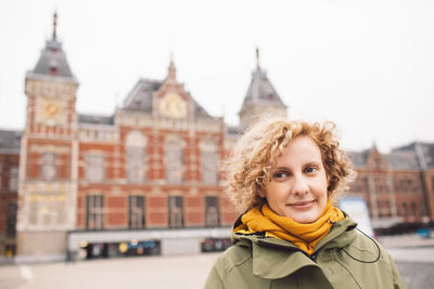 Portrait of smiling woman standing against buildings in city