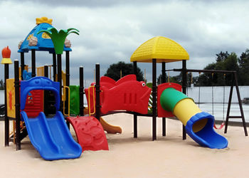 Multi colored chairs in park against blue sky