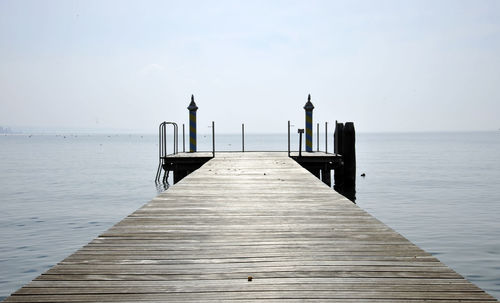 Wooden jetty on pier in sea against sky