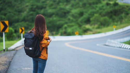 Rear view of woman walking on road