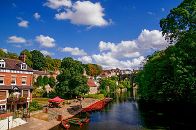 Scenic view of river by buildings against sky