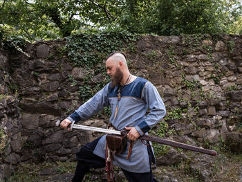 Full length of man holding umbrella while standing against trees