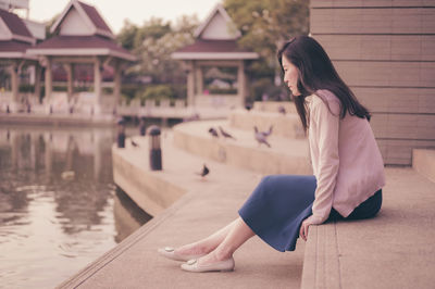 Side view of young woman sitting outdoors