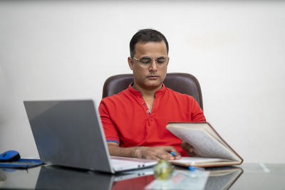 Mid adult man using mobile phone while sitting on table