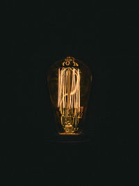 Close-up of illuminated light bulb against black background