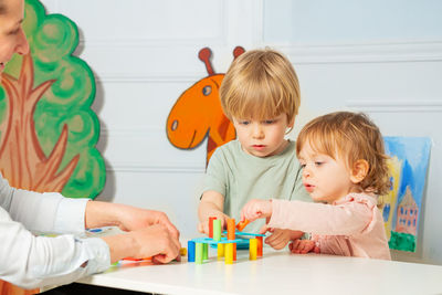 High angle view of mother playing with toys on table