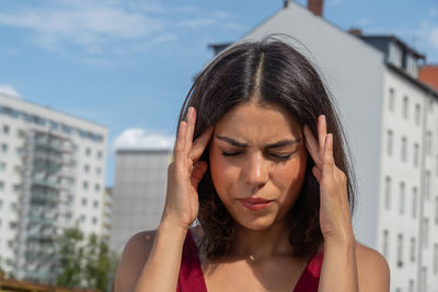 Close-up of woman with headache standing in standing in city