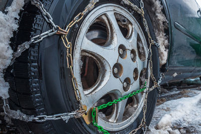 Close-up of a car wheel with snow chains. the fenders of the car are forgotten by the muddy snow.