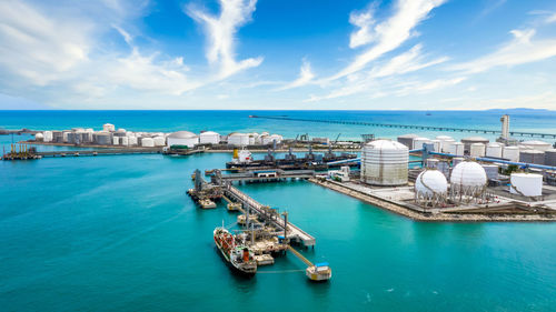 Aerial view oil terminal with storage tank farm, offshore oil rig, tanker and port, land oil rig,