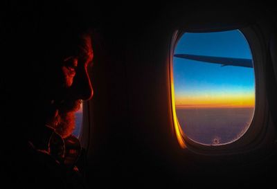 Senior man travelling in airplane during sunset