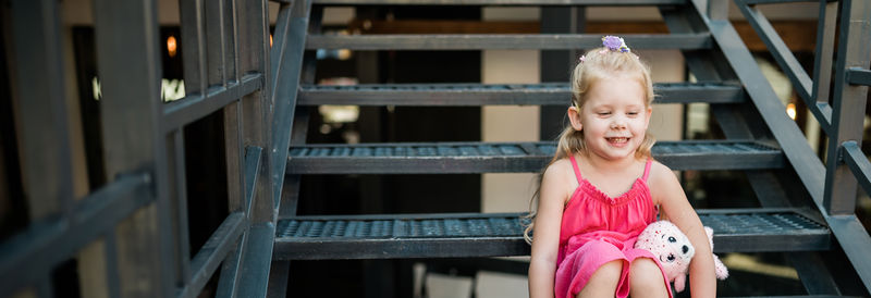 Portrait of young woman standing against building