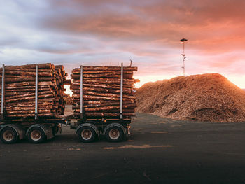 Stack of wood in trailer on road against sky