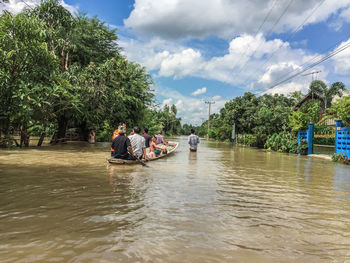People in boat at flooded area against sky
