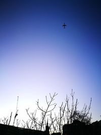 Low angle view of airplane flying against clear blue sky